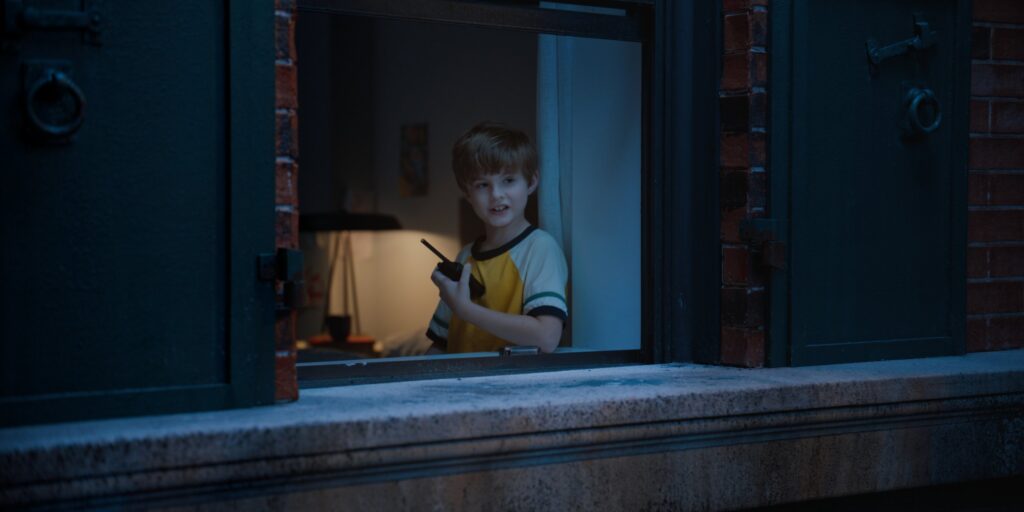 Boy looking out the back alley window in blue hour lighting
