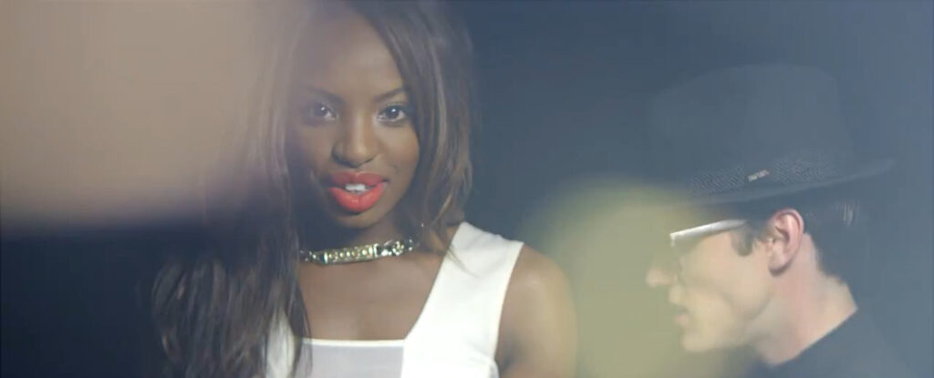 Model looking straight into camera with Sonny dancing next to her