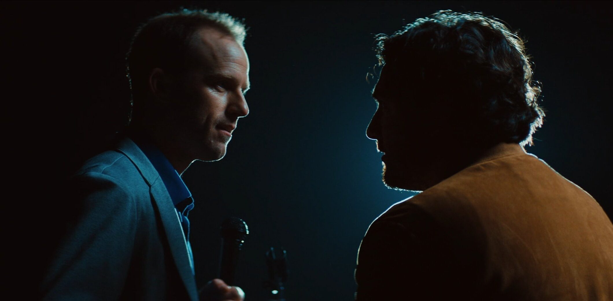 Two men talking to each other in dramatic black void lighting