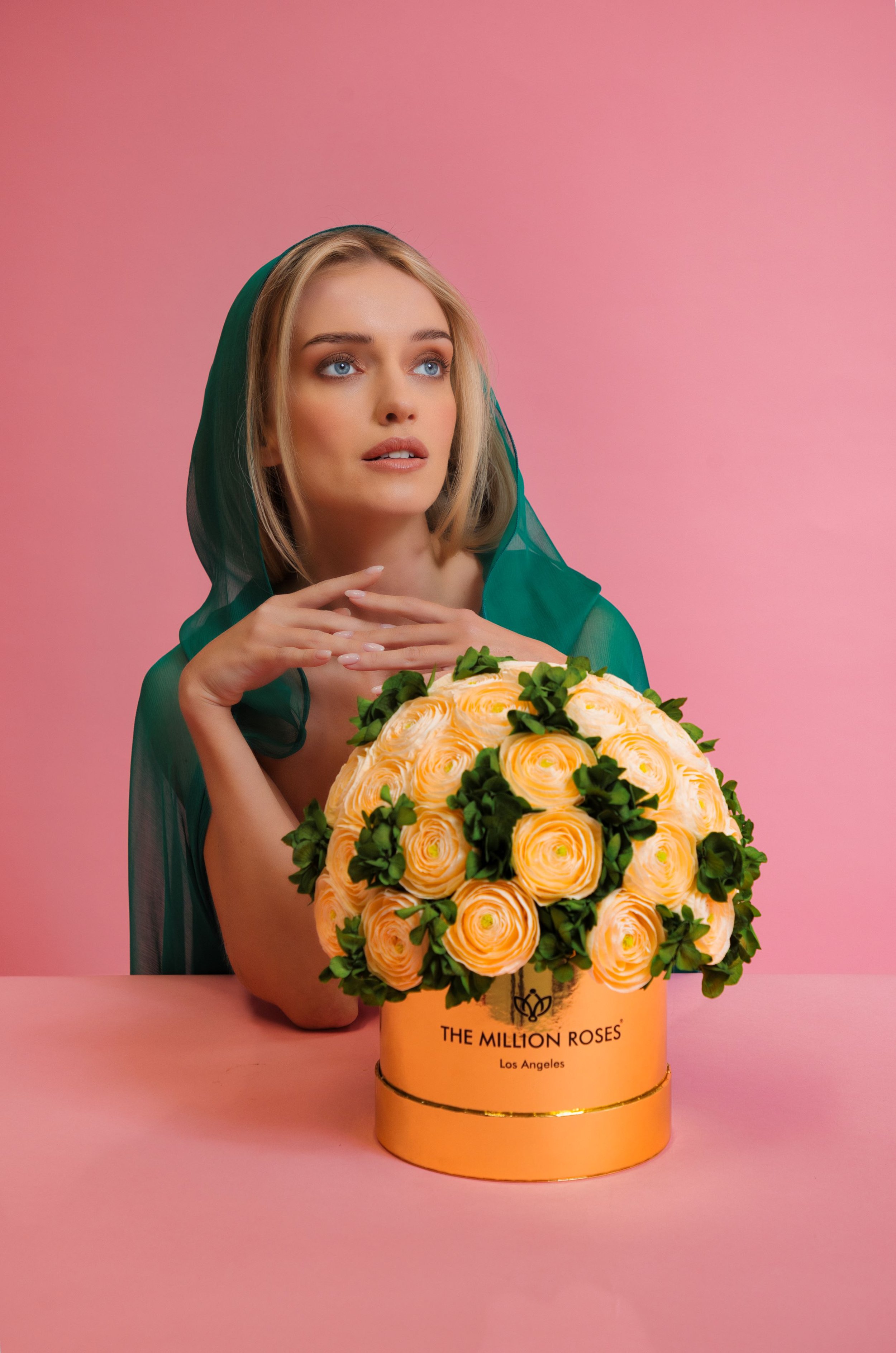 Photo model with green veil presenting The Million Roses flowers in gold box