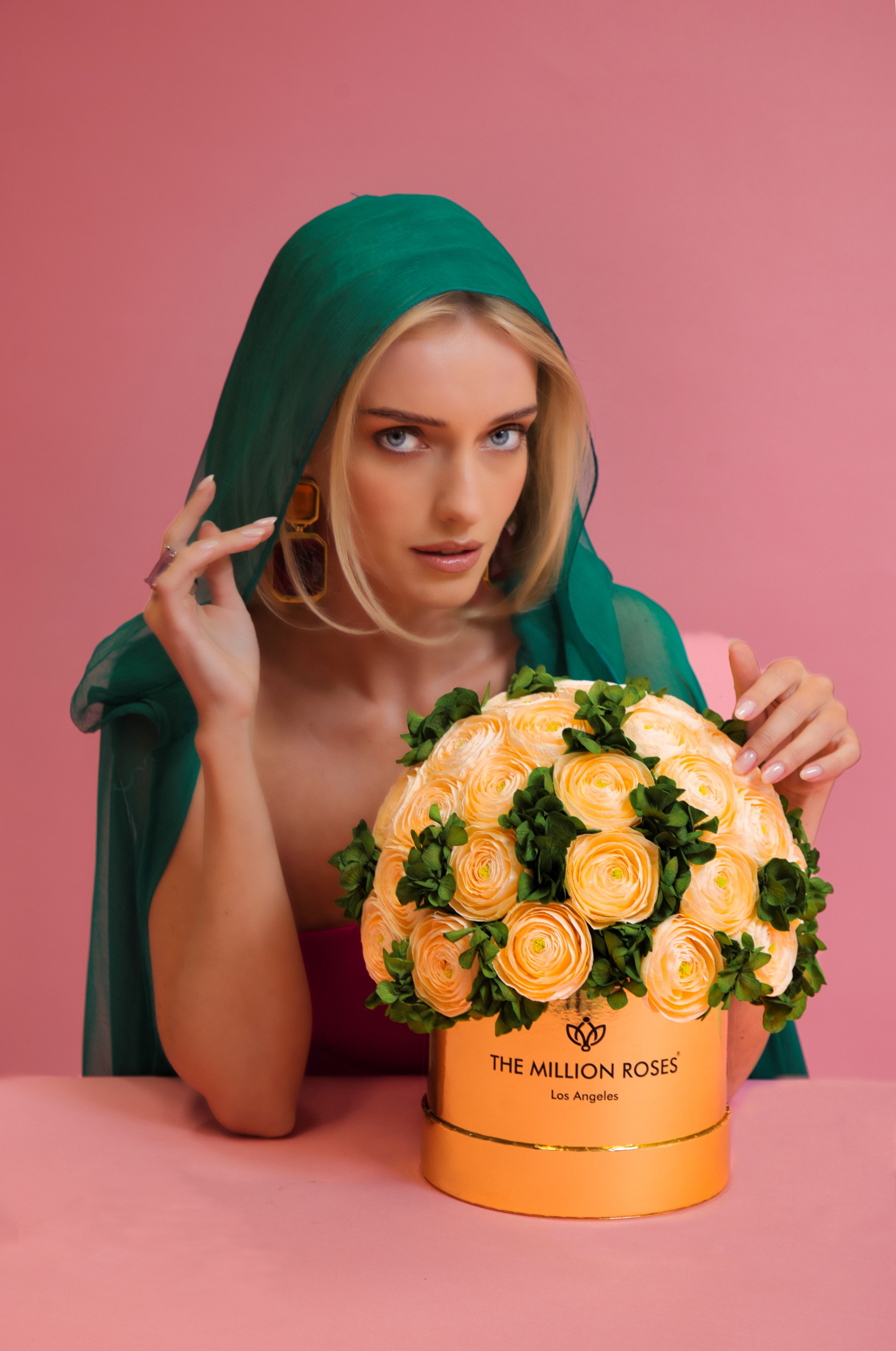 Photo model with green veil presenting yellow The Million Roses flowers in gold box
