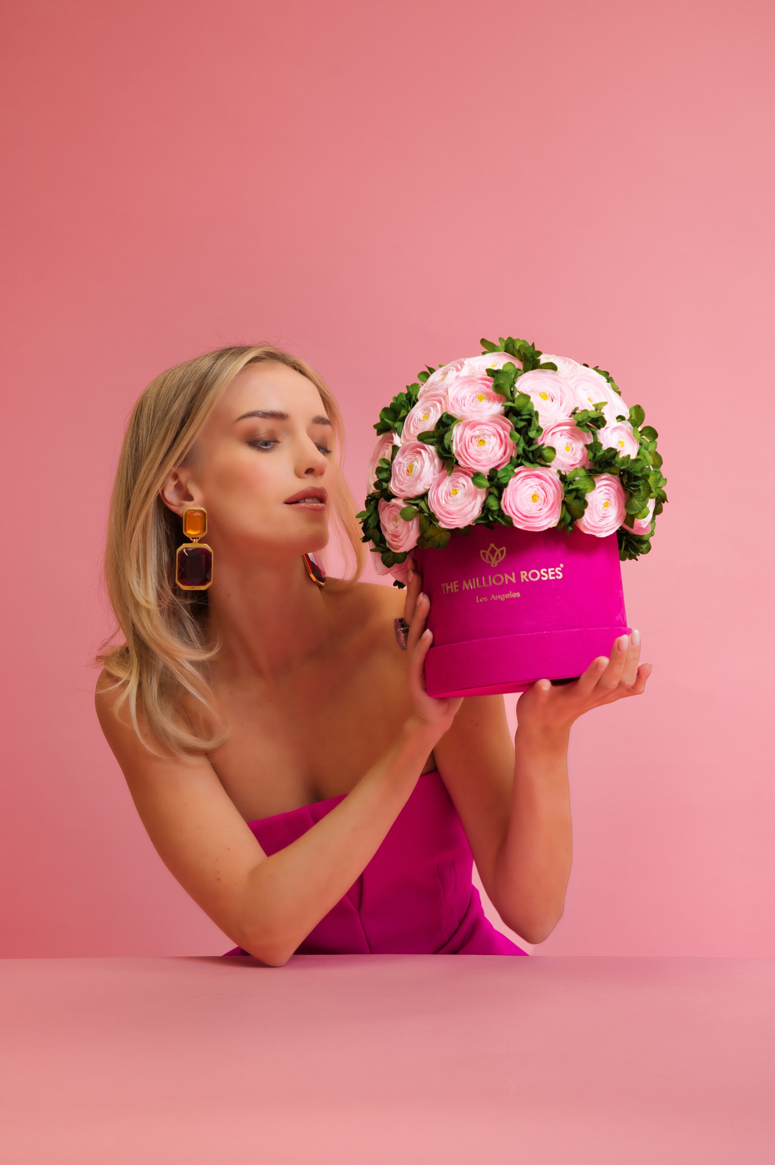 Photo model looking at pink The Million Roses flowers in pink box