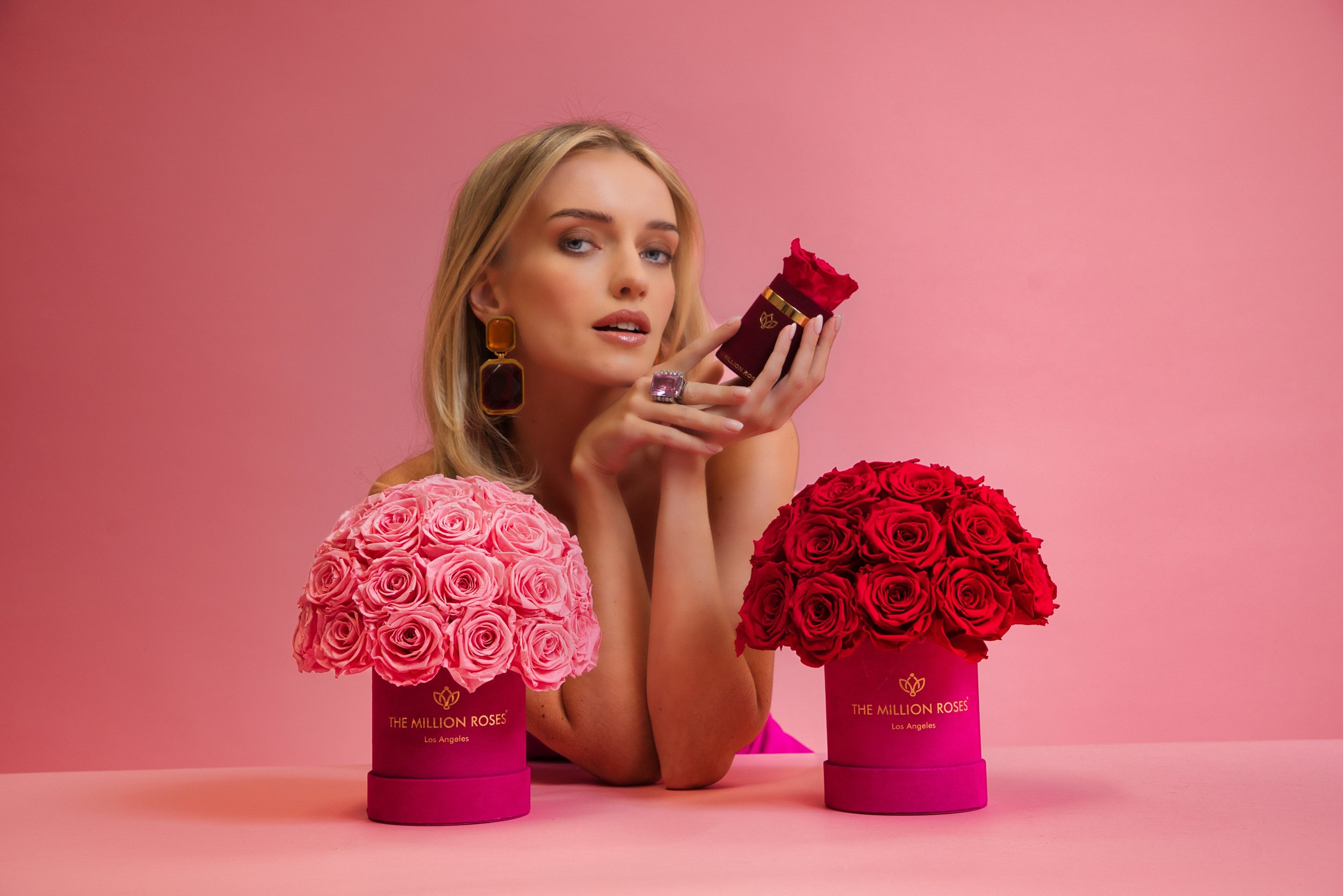 Photo model presenting three different sized The Million Roses flowers boxes to camera