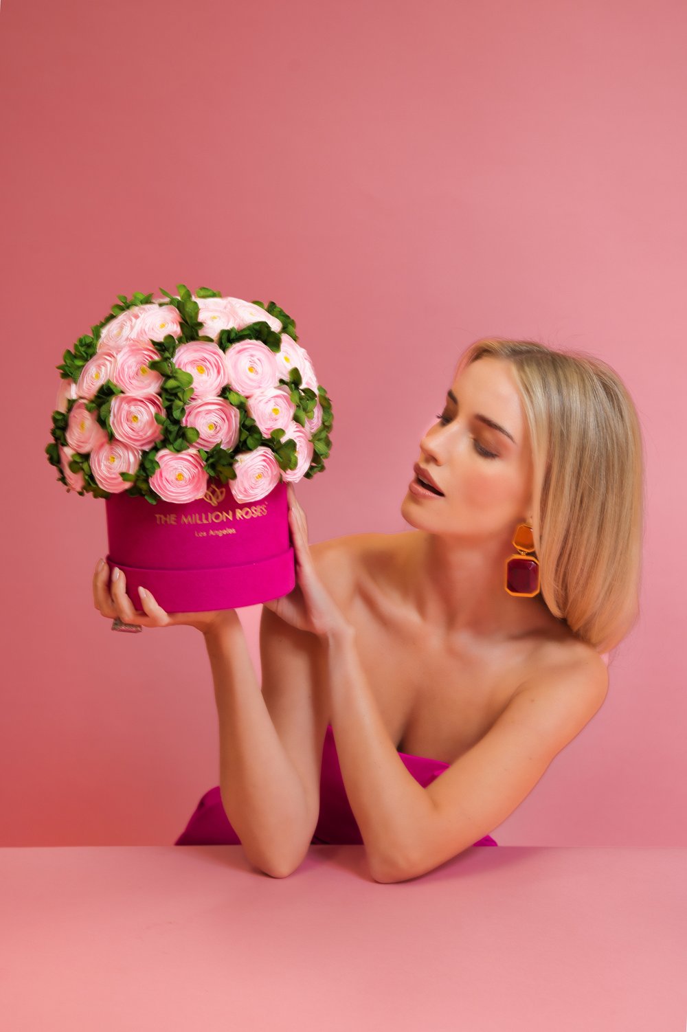Photo model looking at pink The Million Roses flowers in pink box