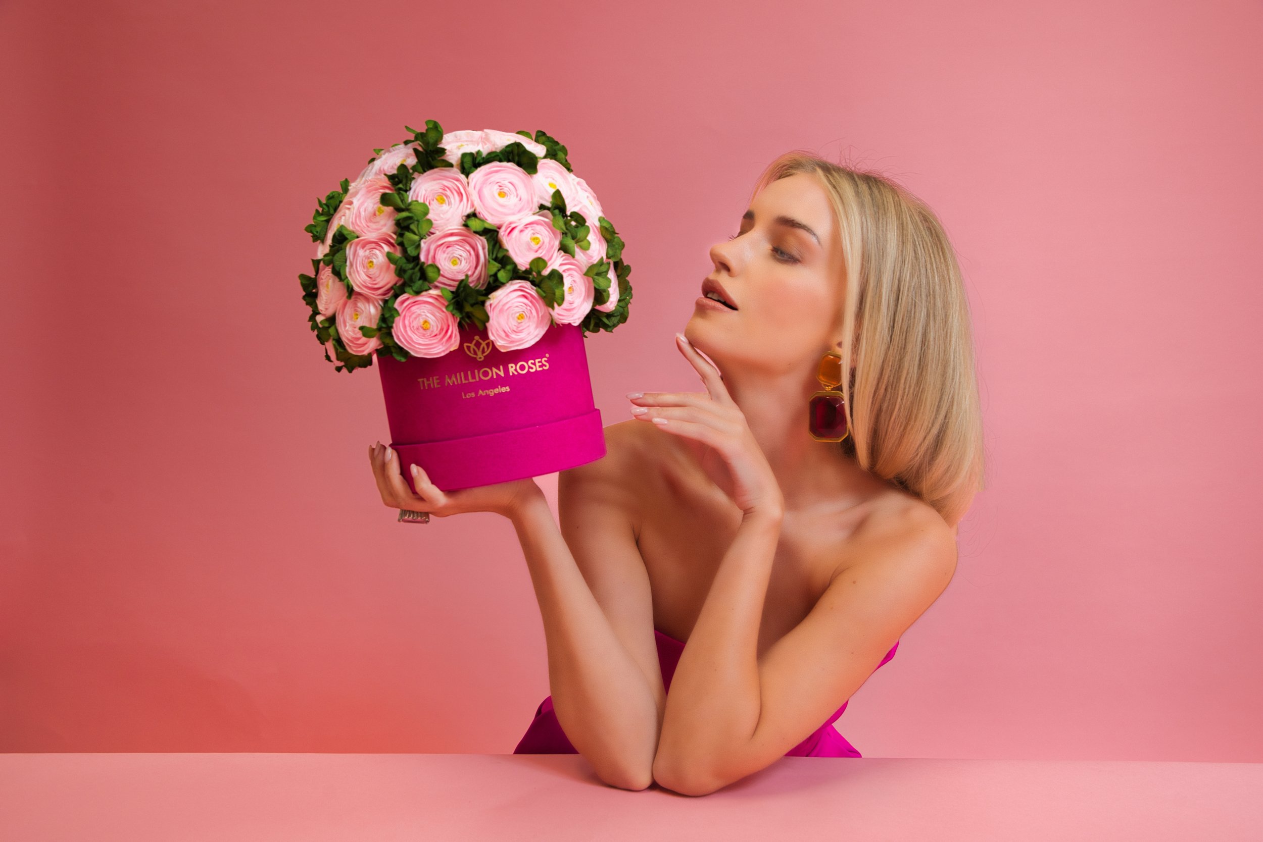 Photo model looking at pink The Million Roses flowers in pink box