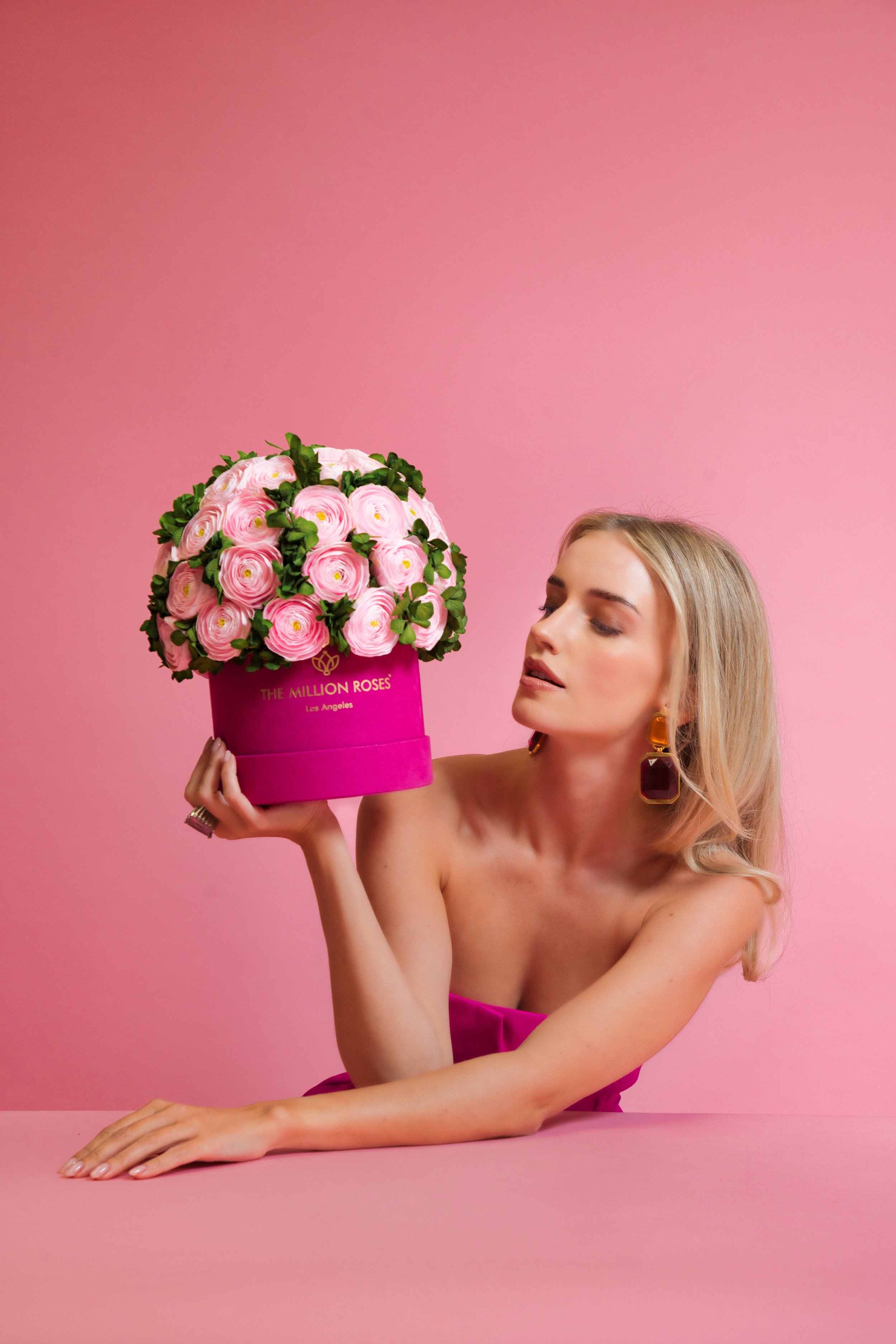 Photo model holding up pink The Million Roses flowers in purple box