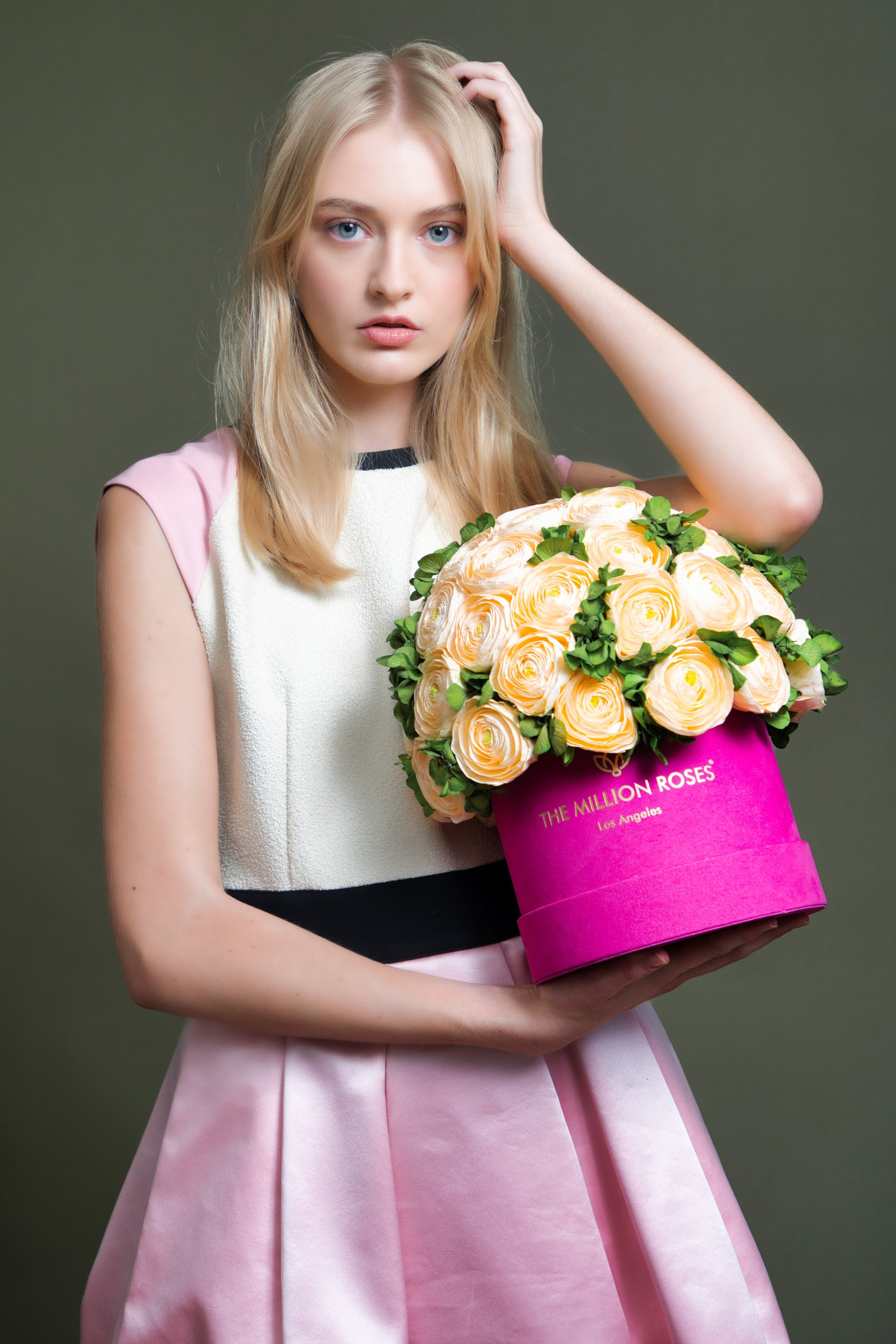 Photo model in white and pink dress presenting yellow The Million Roses flowers in pink box