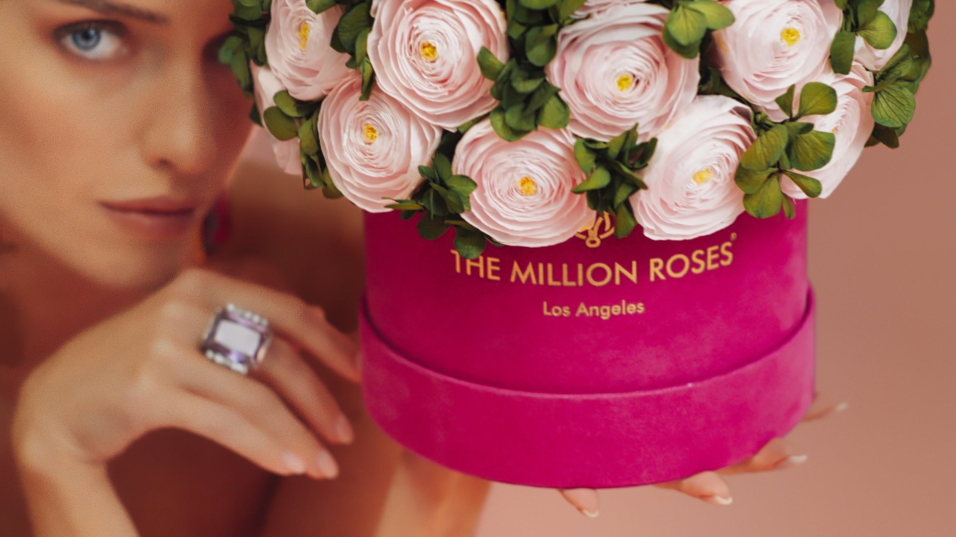 Photo model presenting pink The Million Roses flowers in purple box
