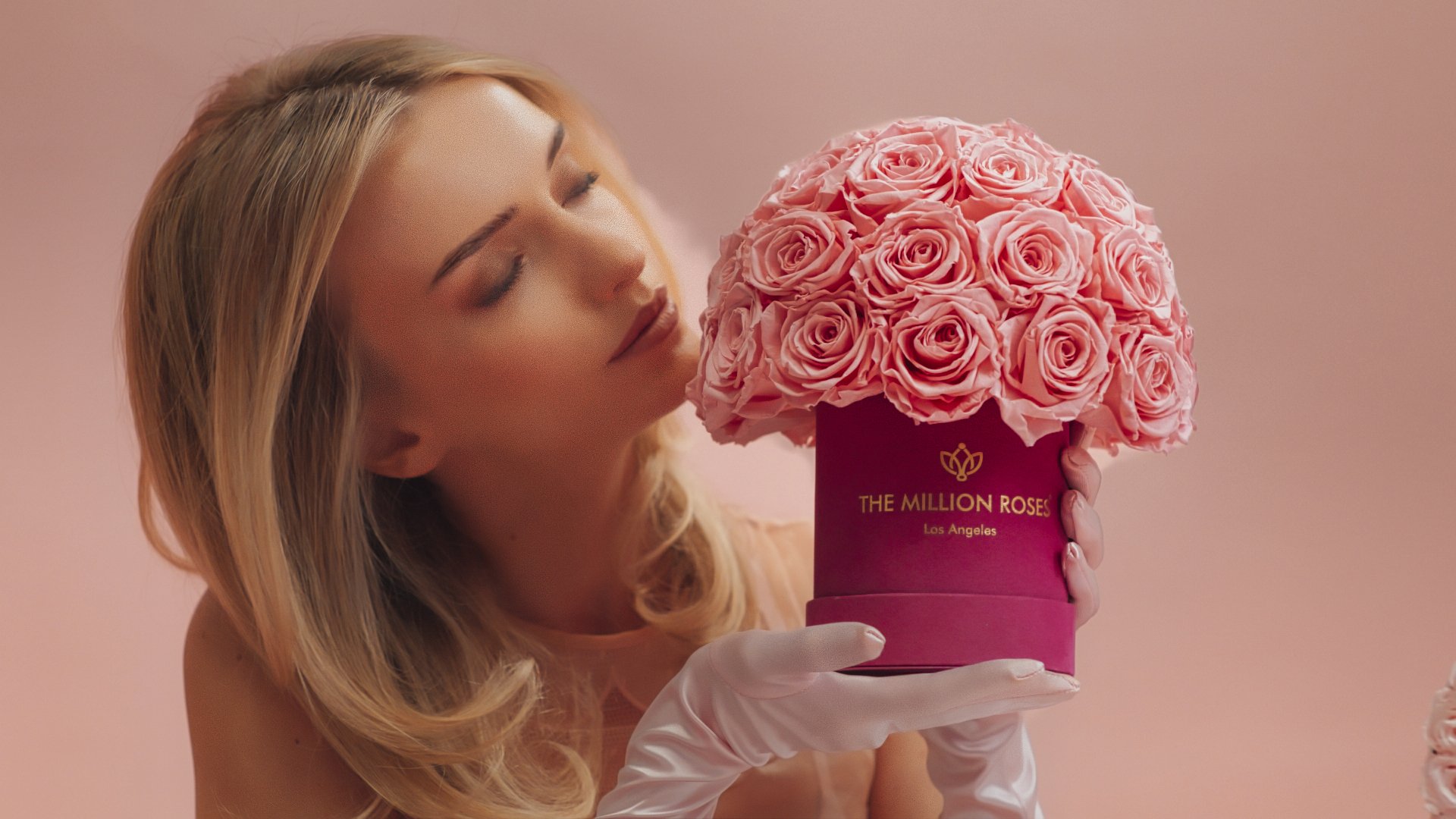 Photo model smelling pink The Million Roses flowers in pink box