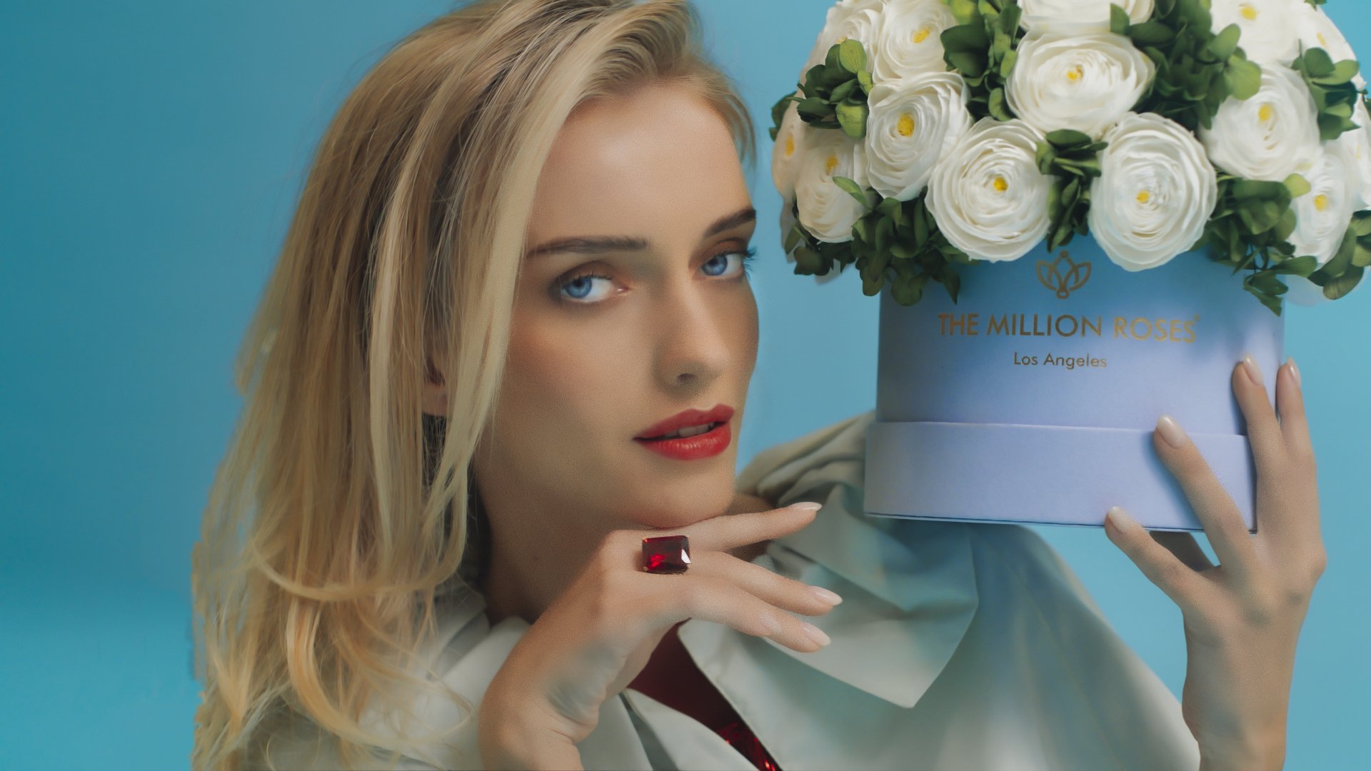 Photo model with green dress presenting white The Million Roses flowers in purple box