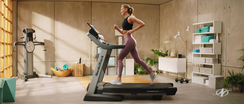 Wide shot of woman running on treadmill machine - tv commercial
