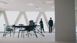 Bright and modern office space with two people looking out a window and an office desk