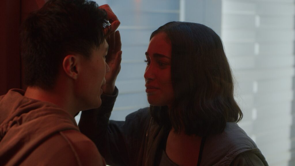 Two person looking at each other through a glass window in red color lighting