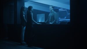 Sci-fi blue scene with three people talking at a desk