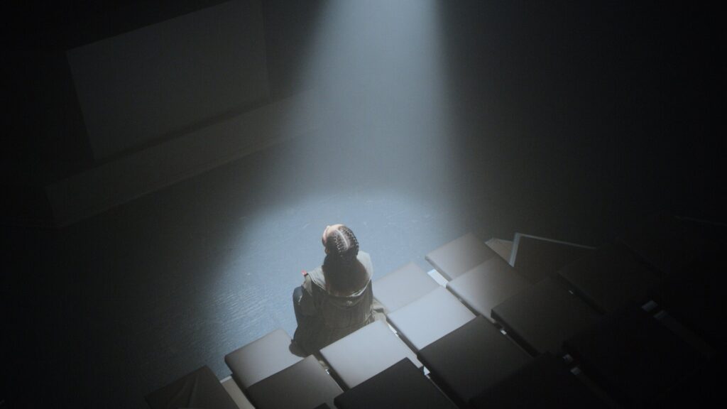 The CW Pandora tv series frame of pandora looking up into a spotlight in dimly lit audtorium