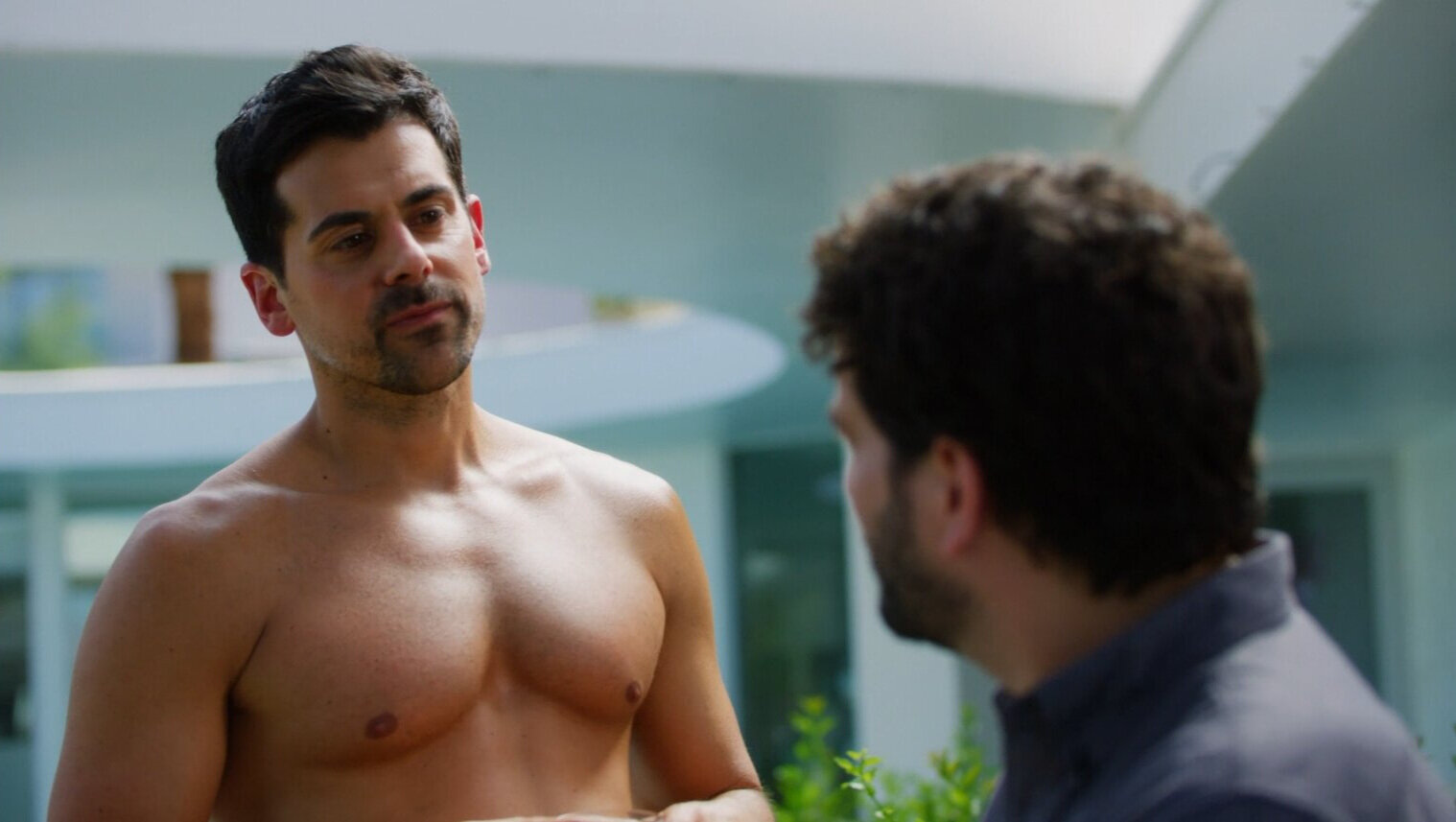 Low angle shot of bear chested man in warm sunlight looking at another man