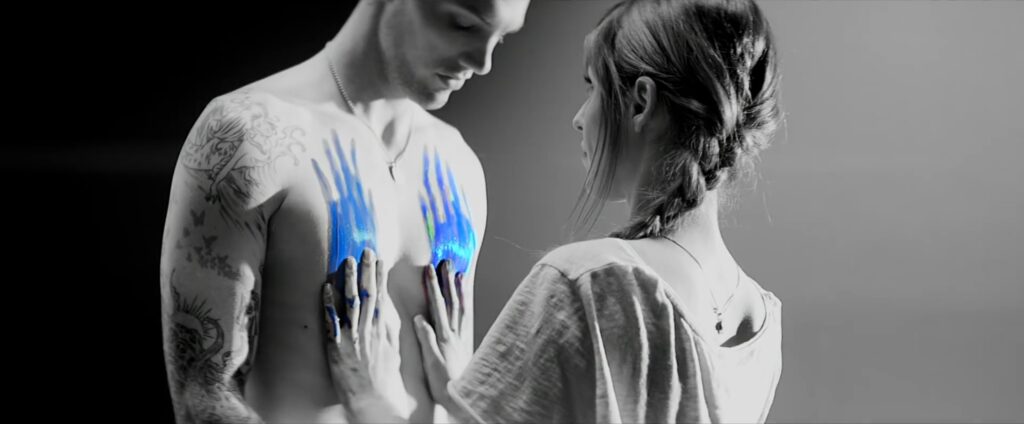 Jenn Ayache smearing paint over models body in dramatic studio lighting set