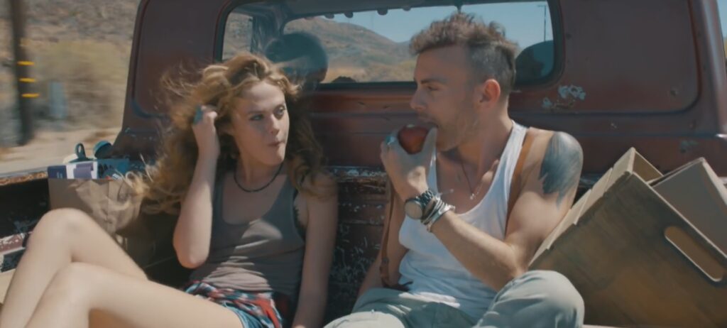 Asaf Avidan and model in back of pick up truck eating an apple