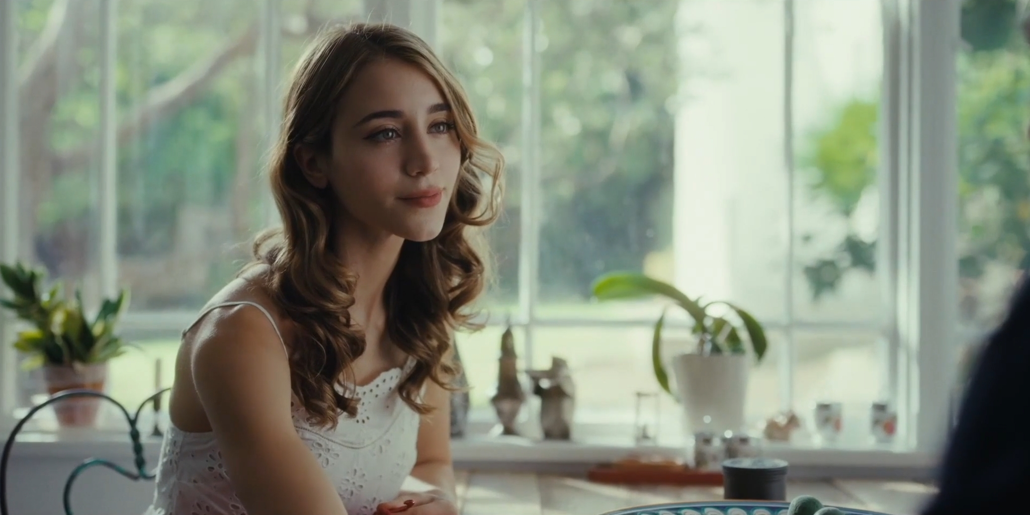 Medium shot of woman sitting at a table with window behind her