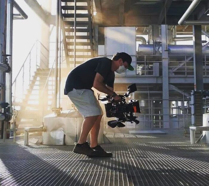 Maximilian Schmige hand held with red raptor camera backlit by smoke in industrial movie set