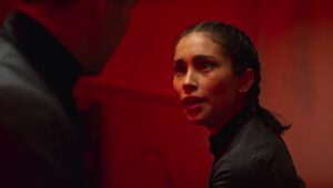 Close up shot of Priscilla Quintana in Pandora series in dramatic red lit scene