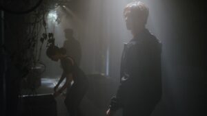 Ben Radcliffe walking through dramatically lit corridor at night