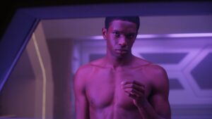 Close up of actor Martin Bobb-Semple looking through window in purple light