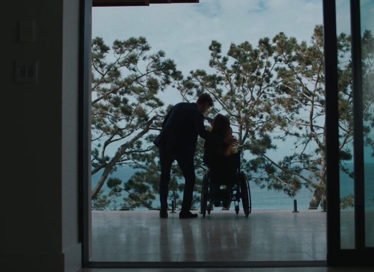Woman in wheelchair outside a balcony next to a man