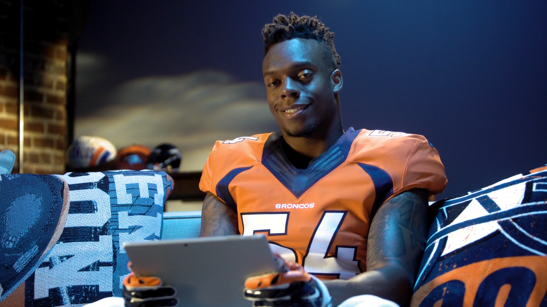Brandon Marshall holding an ipad sitting on a couch