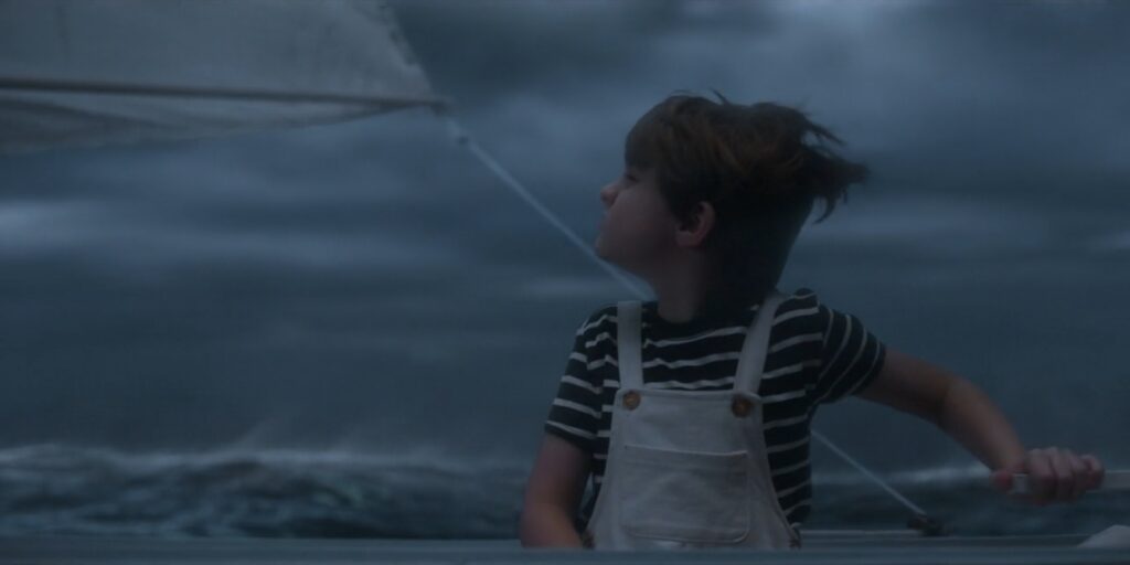Boy steering a boat in a stormy sea