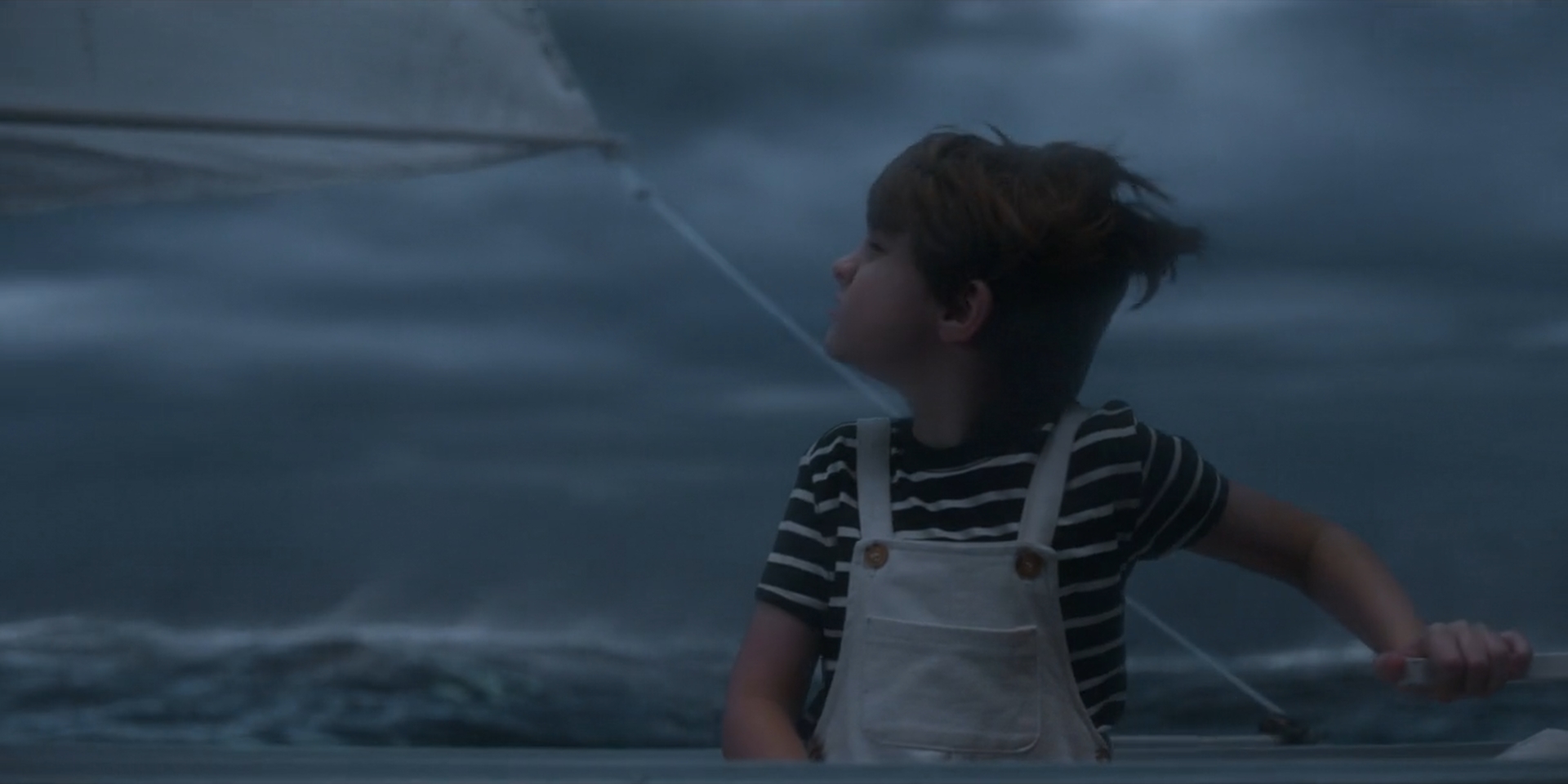 Boy steering a boat in a stormy sea