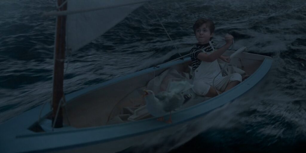 Wide shot of a boy steering a boat in a stormy sea