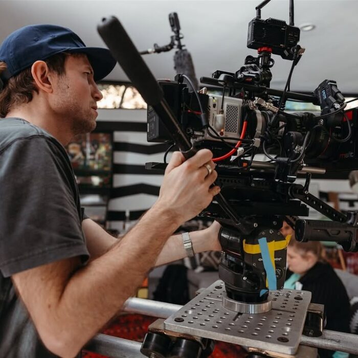 Cinematographer Maximilian Schmige operating red komodo camera on dolly tracks on set.