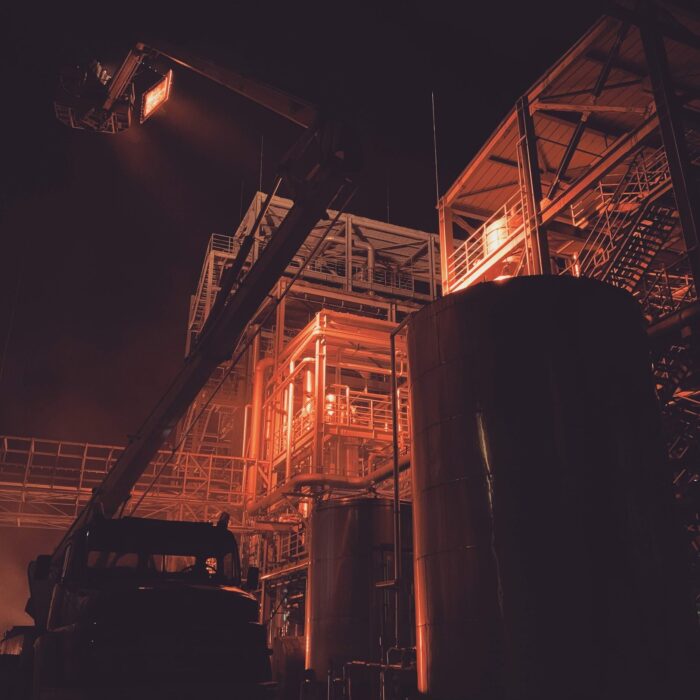 Night exterior industrial warehouse space in orange lighting with large crane lighting up the building at night