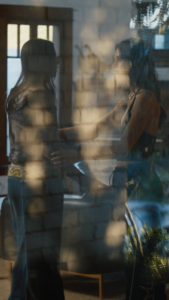 Two people standing in room seen through outside window with reflections